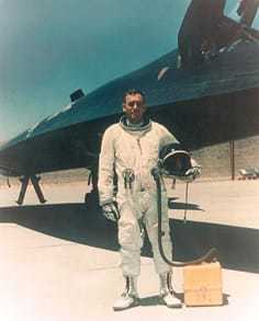 An A-12 Oxcart pilot in a pilot's suit standing in front of the plane.